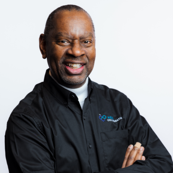 Smiling professional man in black chef jacket with arms crossed.